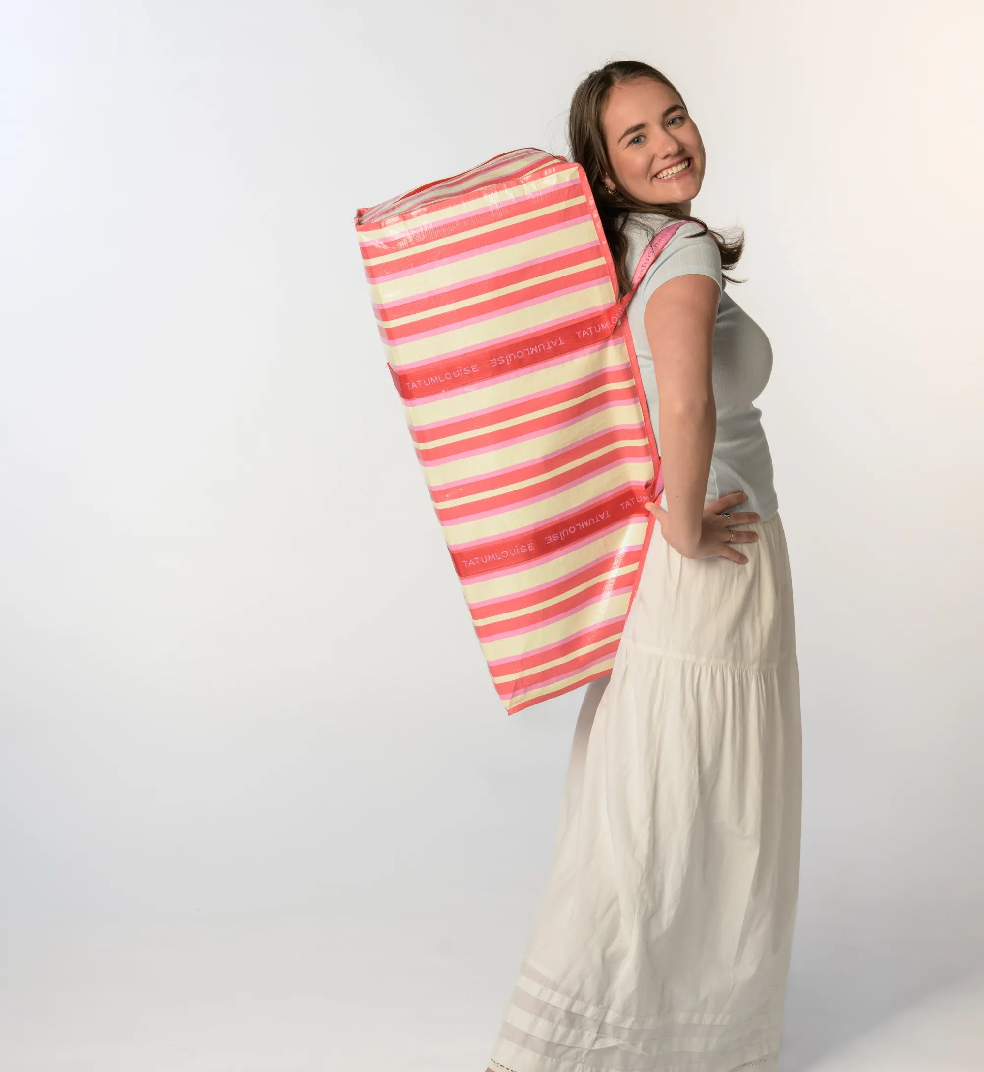 Founder of Tatum Louise holding a pink and white striped moving bag against a white background