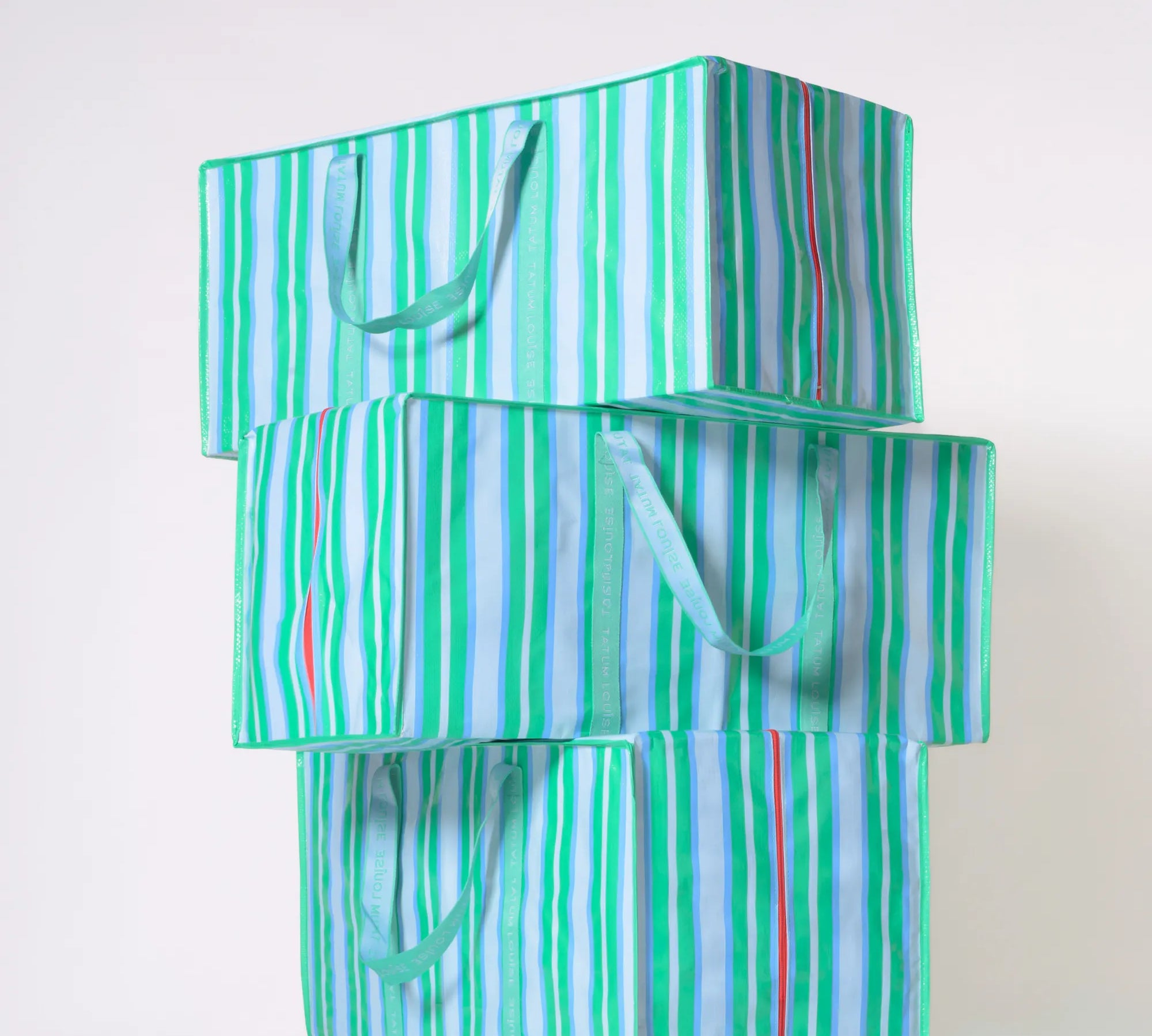 Stack of green and white striped eco-friendly moving bags on a white background