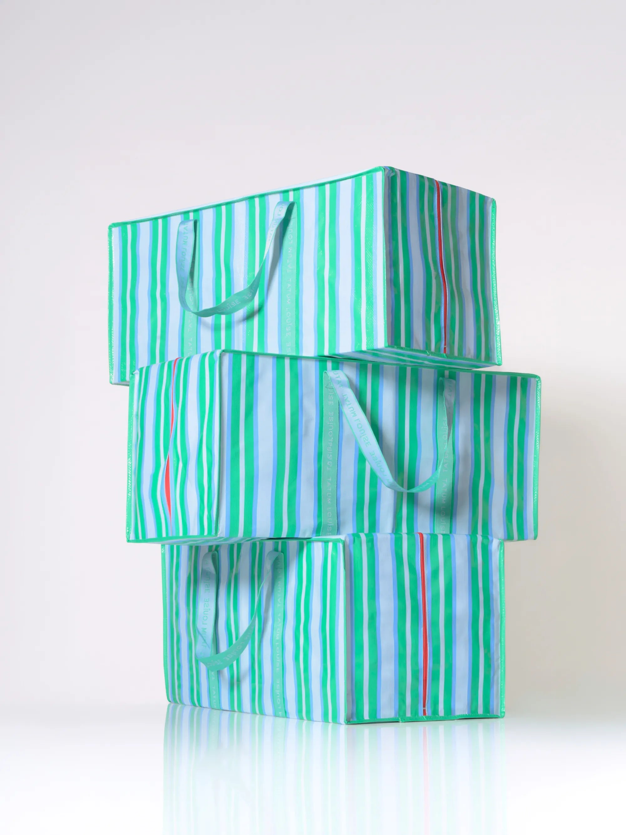 Stack of green and white striped eco-friendly moving bags on a white background