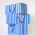 Blue striped reusable moving bag with handles on a white background