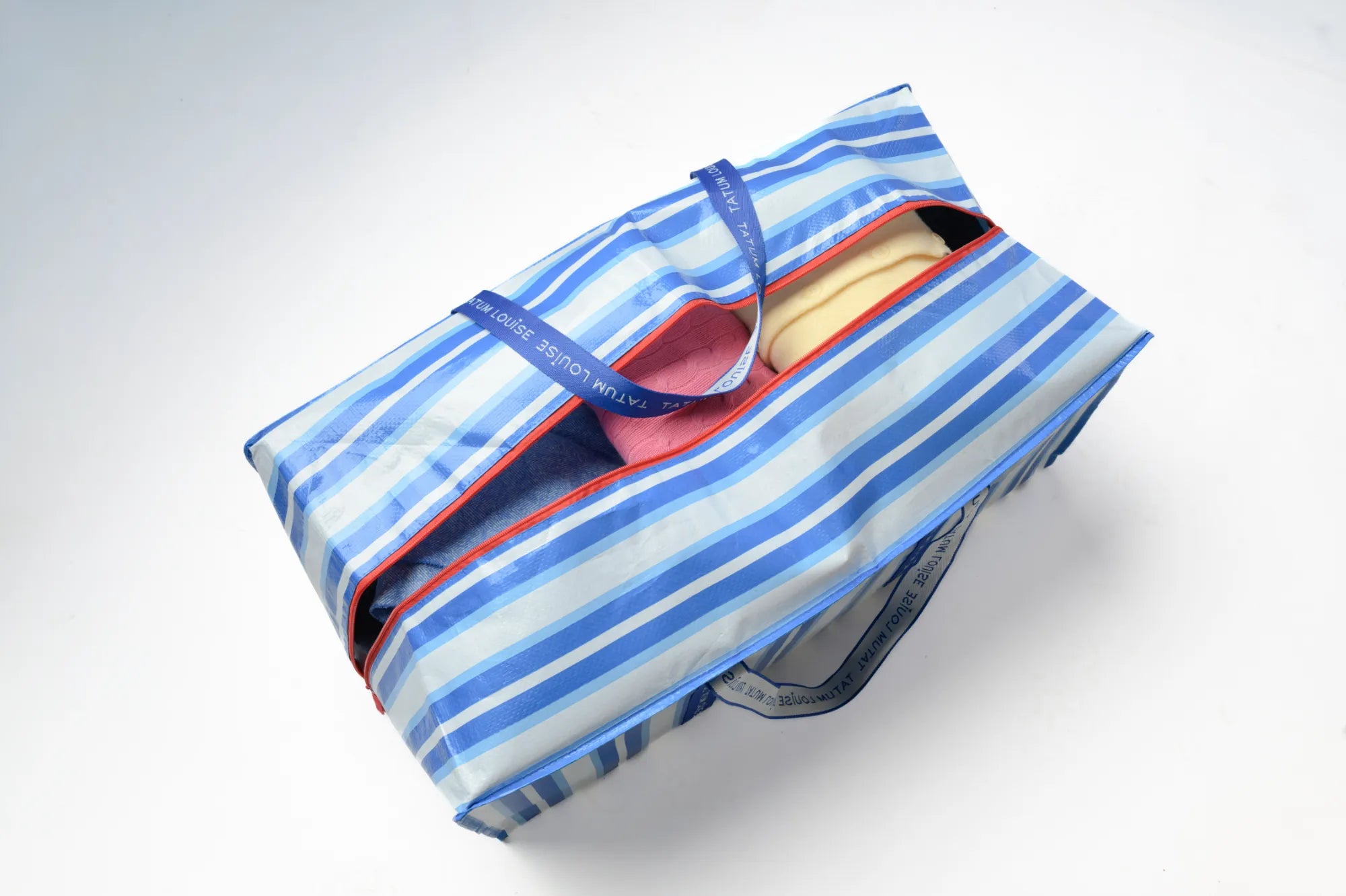 Blue and white striped college move-in bag with a red zipper on a white background