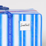 Striped blue and white dorm moving bag with water-resistant label holder.