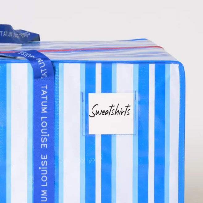 Striped blue and white dorm moving bag with water-resistant label holder.