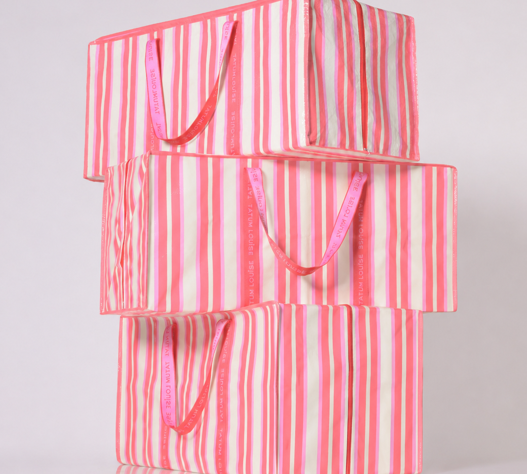 Stack of pink and white striped reusable moving bags for college on a white background