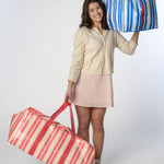 Girl holding one Marina Blue striped moving bag and one Peony Pink striped moving bag from TATUM LOUISE's collection of stylish, reusable bags.