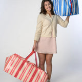 Girl holding one Marina Blue striped moving bag and one Peony Pink striped moving bag from TATUM LOUISE's collection of stylish, reusable bags.